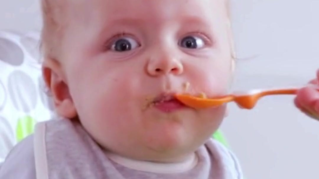Baby being spoon-fed a first taste of puree