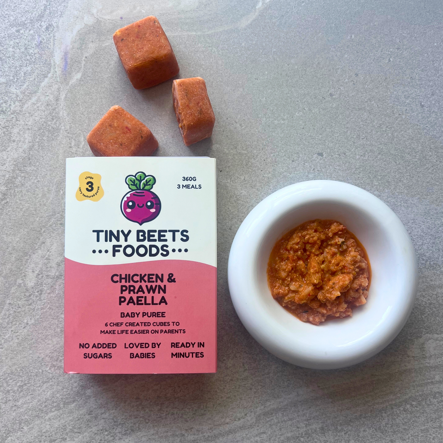 Tiny Beets Foods packaging with a bowl of baby food puree on a gray surface