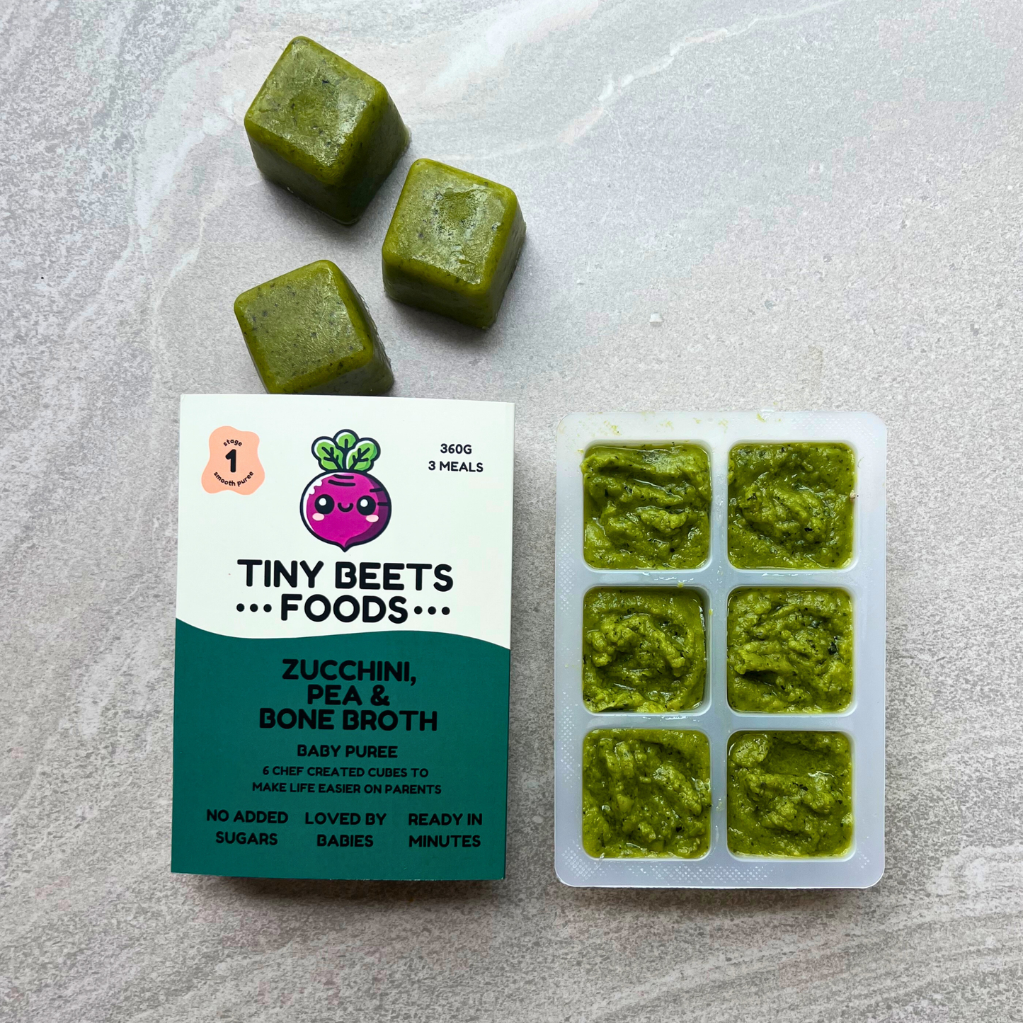 Green baby food cubes with packaging on a light gray surface