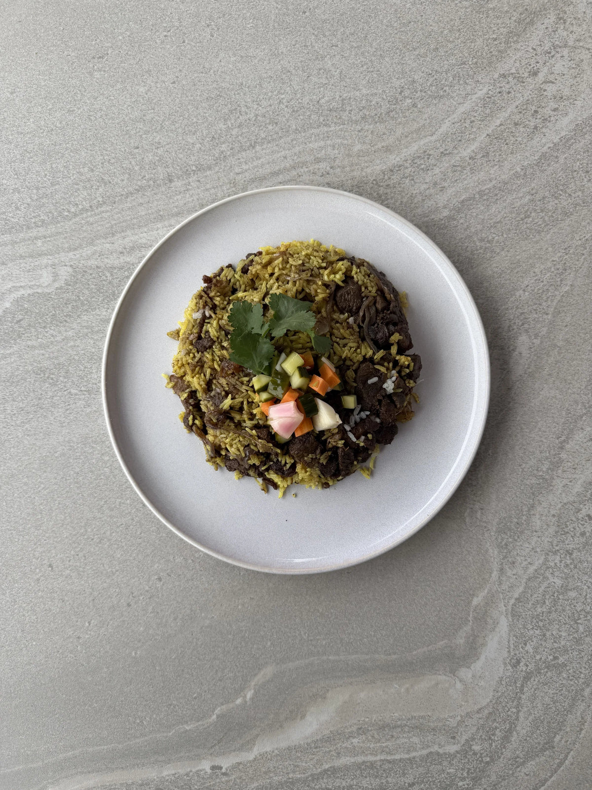 Tiny Beets Lamb Biryani family meal on a plate, slow-cooked lamb and turmeric basmati rice topped with Indo pickle